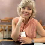 Heike Geiling at a desk holding a mobile phone.